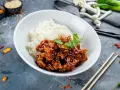 Pyszny kurczak bac bo w sosie z sezamem, podany z ryżem. Obok pałeczki i papryczki chili.