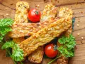Złociste kawałki tempeh, smażone na złoto, z pomidorkami i natką pietruszki. Tempeh co to? To pyszna, roślinna alternatywa.