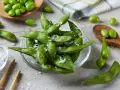 Misternie ułożone strąki edamame, posypane solą, kuszą swoim zielonym kolorem. Czy wiesz, edamame co to? To młoda soja, pyszna przekąska!