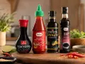 Cztery butelki sosów: sojowy, sriracha, ponzu i teriyaki, gotowe do sushi.