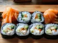 Rolki sushi z ogórkiem i łososiem, podane z marynowanym imbirem i zielonymi dodatkami.