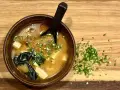 Miseczka aromatycznej zupy miso z tofu i wodorostami, posypana szczypiorkiem. Idealna na rozgrzewkę.