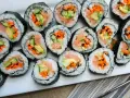 Ułożone na talerzu rolki sushi z łososiem, awokado, ogórkiem i marchewką. Widać, co do sushi do środka, czyli świeże składniki.