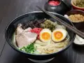 Parujący ramen: makaron, plastry wieprzowiny, jajko na pół, szczypiorek i grzyby. Pyszne danie, które rozgrzewa.