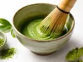 Przygotowanie idealnego matcha: zielony proszek, bambusowa miotełka i spieniony napój w miseczce.