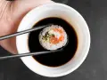 Pałeczkami zanurzam sushi w sosie kabayaki.