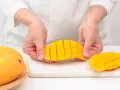 Ręce trzymają pokrojonego w kostkę mango. Ten soczysty owoc jest gotowy do jedzenia.