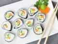 Smaczne futomaki z awokado, ogórkiem i marchewką, udekorowane natką pietruszki i wasabi.