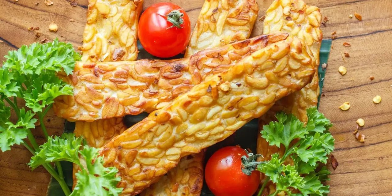 Złociste kawałki tempeh, smażone na złoto, z pomidorkami i natką pietruszki. Tempeh co to? To pyszna, roślinna alternatywa.