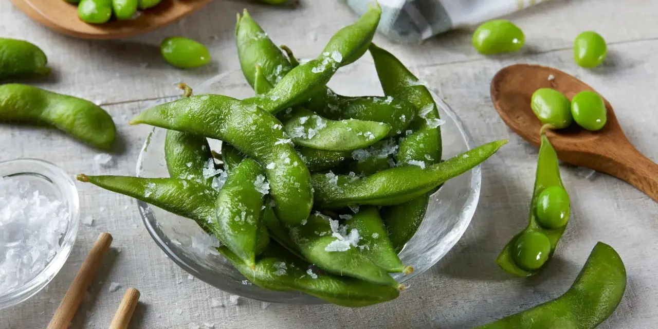 Misternie ułożone strąki edamame, posypane solą, kuszą swoim zielonym kolorem. Czy wiesz, edamame co to? To młoda soja, pyszna przekąska!