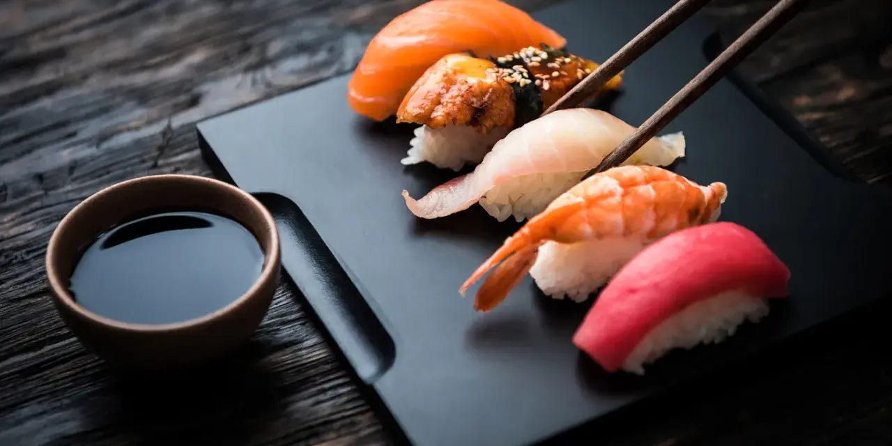 Zestaw sushi z łososiem, krewetką i tuńczykiem, gotowy do zanurzenia w sosie shoyu.