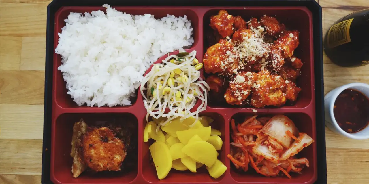 Bento box z ryżem, kurczakiem w sosie, kimchi, fasolką i żółtą rzodkiewką.