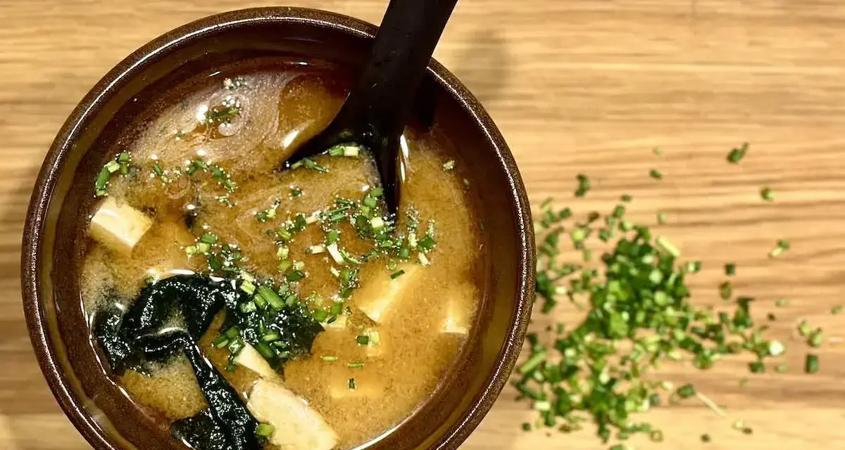 Miseczka aromatycznej zupy miso z tofu i wodorostami, posypana szczypiorkiem. Idealna na rozgrzewkę.