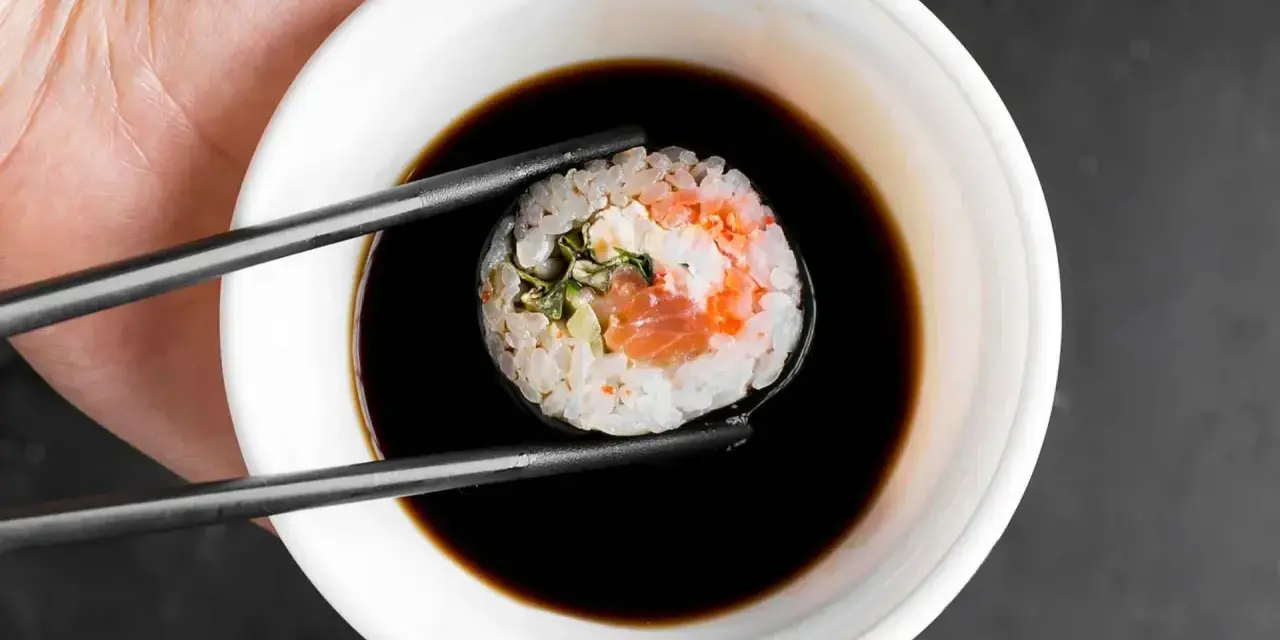 Pałeczkami zanurzam sushi w sosie kabayaki.