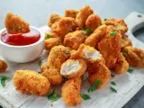 Chrupiące kawałki kurczaka w panierce z bułki tartej panko, podane z ketchupem i posypane natką pietruszki.