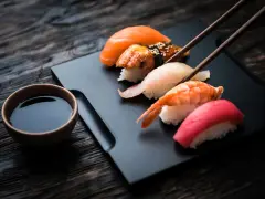 Zestaw sushi z łososiem, krewetką i tuńczykiem, gotowy do zanurzenia w sosie shoyu.
