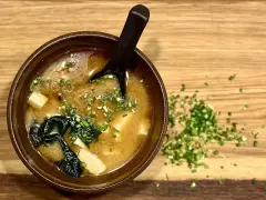 Miseczka aromatycznej zupy miso z tofu i wodorostami, posypana szczypiorkiem. Idealna na rozgrzewkę.