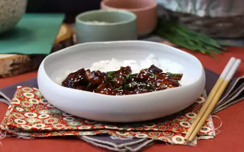Pyszny kurczak po japońsku w sosie teriyaki, podany z ryżem i posypany sezamem.