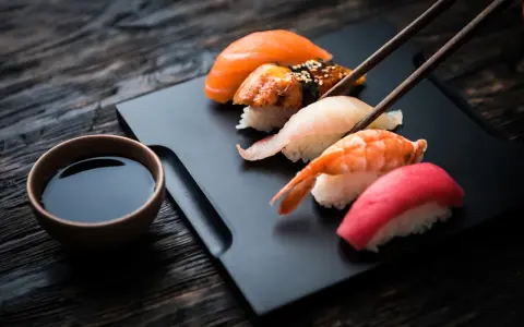 Zestaw sushi z łososiem, krewetką i tuńczykiem, gotowy do zanurzenia w sosie shoyu.