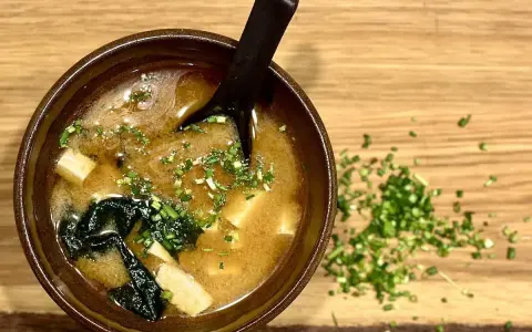 Miseczka aromatycznej zupy miso z tofu i wodorostami, posypana szczypiorkiem. Idealna na rozgrzewkę.