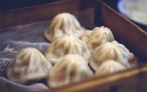 Pyszne, parujące dim sum w bambusowym koszyku. Delikatne pierożki kuszą swoim wyglądem.
