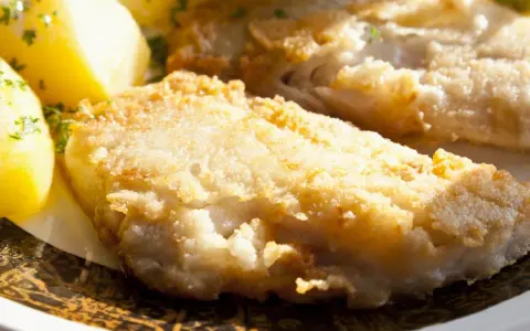 Smażona ryba w panierce z ziemniakami i natką pietruszki.