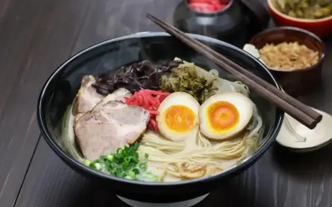 Parujący ramen: makaron, plastry wieprzowiny, jajko na pół, szczypiorek i grzyby. Pyszne danie, które rozgrzewa.