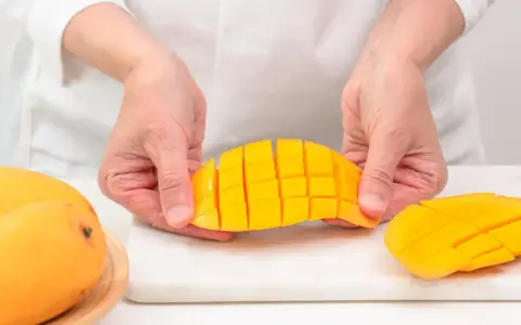Ręce trzymają pokrojonego w kostkę mango. Ten soczysty owoc jest gotowy do jedzenia.
