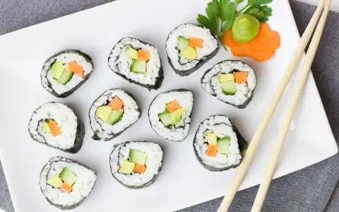 Smaczne futomaki z awokado, ogórkiem i marchewką, udekorowane natką pietruszki i wasabi.