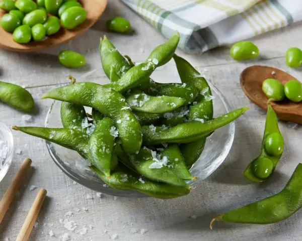 Misternie ułożone strąki edamame, posypane solą, kuszą swoim zielonym kolorem. Czy wiesz, edamame co to? To młoda soja, pyszna przekąska!