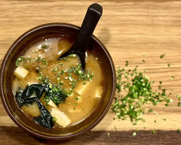 Miseczka aromatycznej zupy miso z tofu i wodorostami, posypana szczypiorkiem. Idealna na rozgrzewkę.