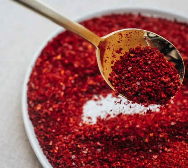 Złota łyżka nabiera gochugaru, koreańskich płatków chili. To właśnie gochugaru co to za przyprawa?
