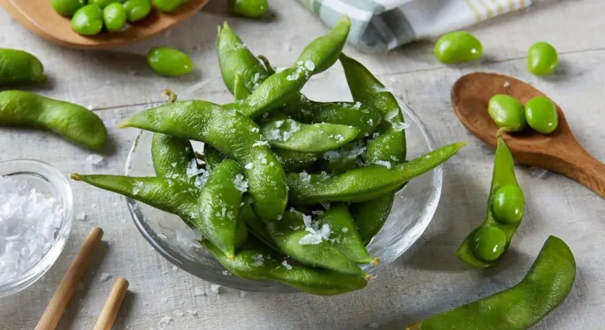 Misternie ułożone strąki edamame, posypane solą, kuszą swoim zielonym kolorem. Czy wiesz, edamame co to? To młoda soja, pyszna przekąska!