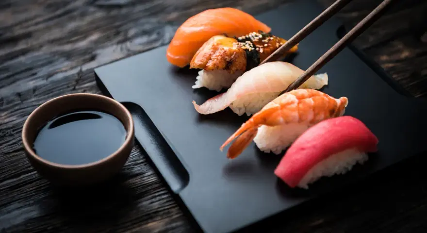 Zestaw sushi z łososiem, krewetką i tuńczykiem, gotowy do zanurzenia w sosie shoyu.