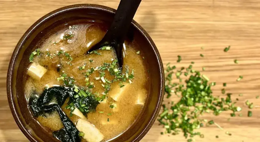 Miseczka aromatycznej zupy miso z tofu i wodorostami, posypana szczypiorkiem. Idealna na rozgrzewkę.