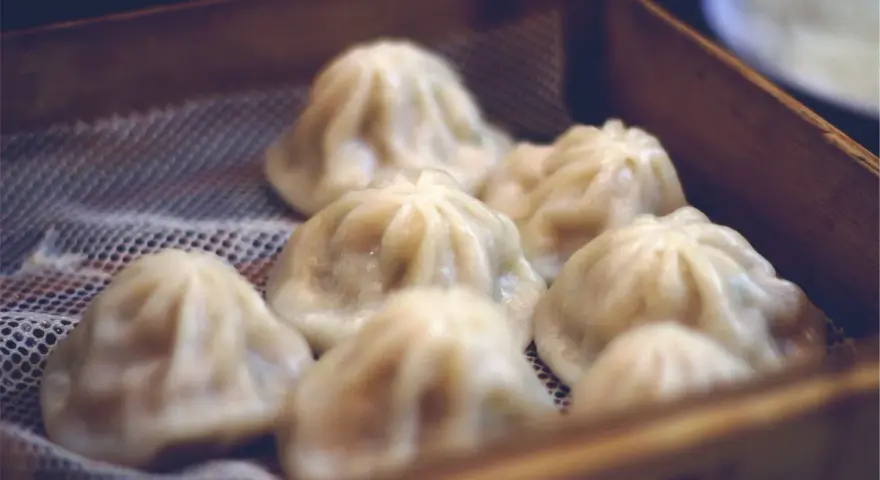 Pyszne, parujące dim sum w bambusowym koszyku. Delikatne pierożki kuszą swoim wyglądem.