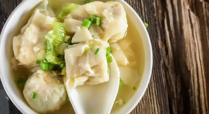 Miseczka aromatycznej zupy z wontonami, gdzie delikatne ciasto do wontonów otula pyszne nadzienie. Posypana szczypiorkiem.