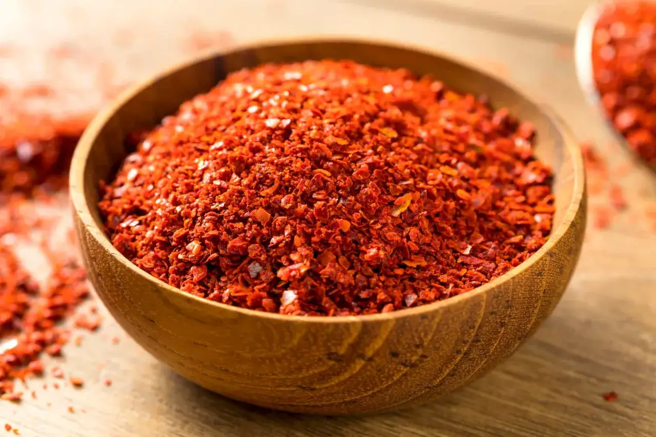 Misternie rozdrobnione płatki chili w drewnianej misce. To właśnie gochugaru, koreańska przyprawa, która nadaje potrawom pikantności i koloru.