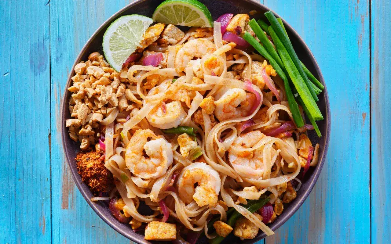 Pad Thai na talerzu z limonką i orzeszkami