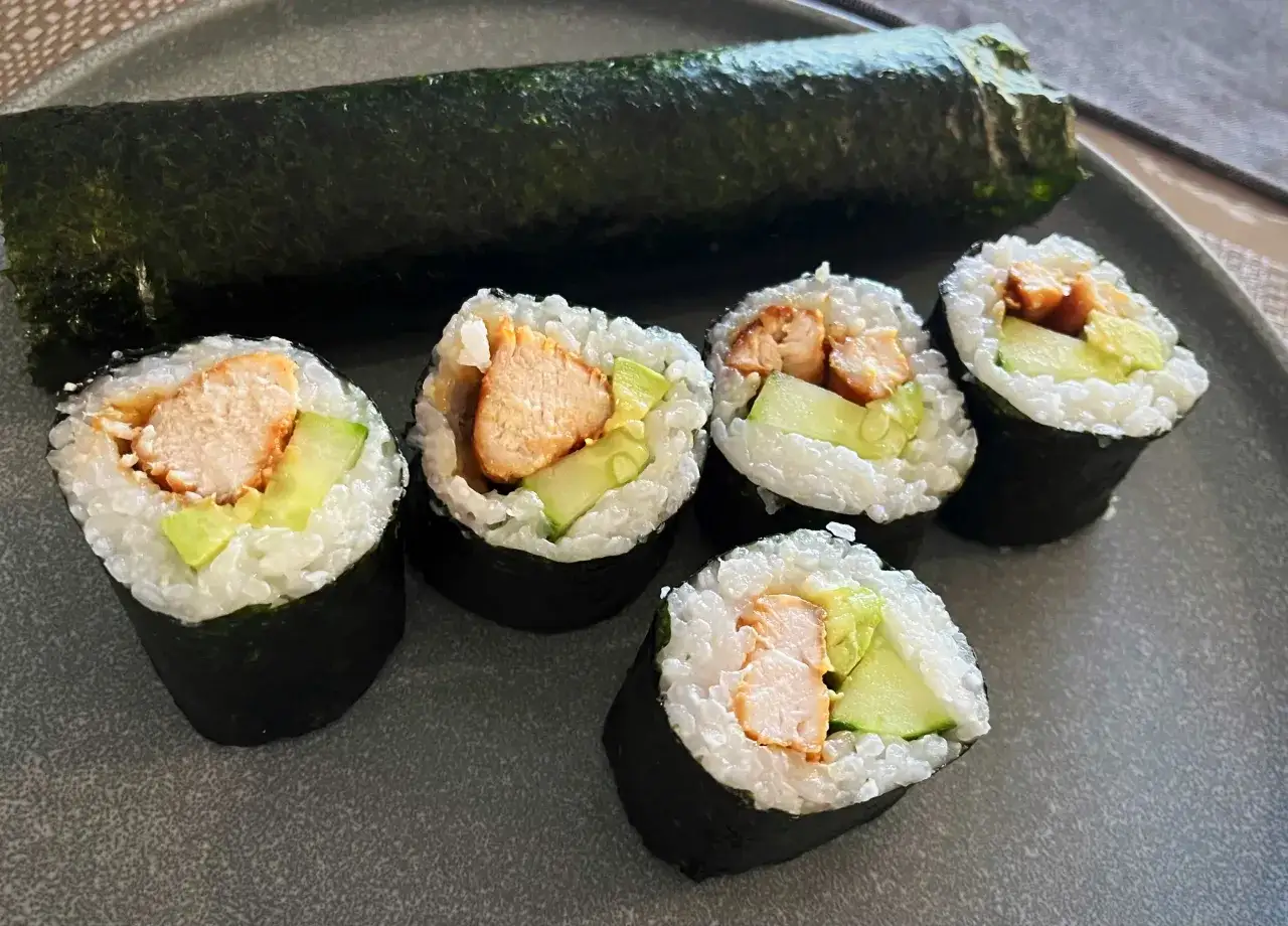 Pięć kawałków sushi z kurczakiem i ogórkiem, obok zwinięty nori.