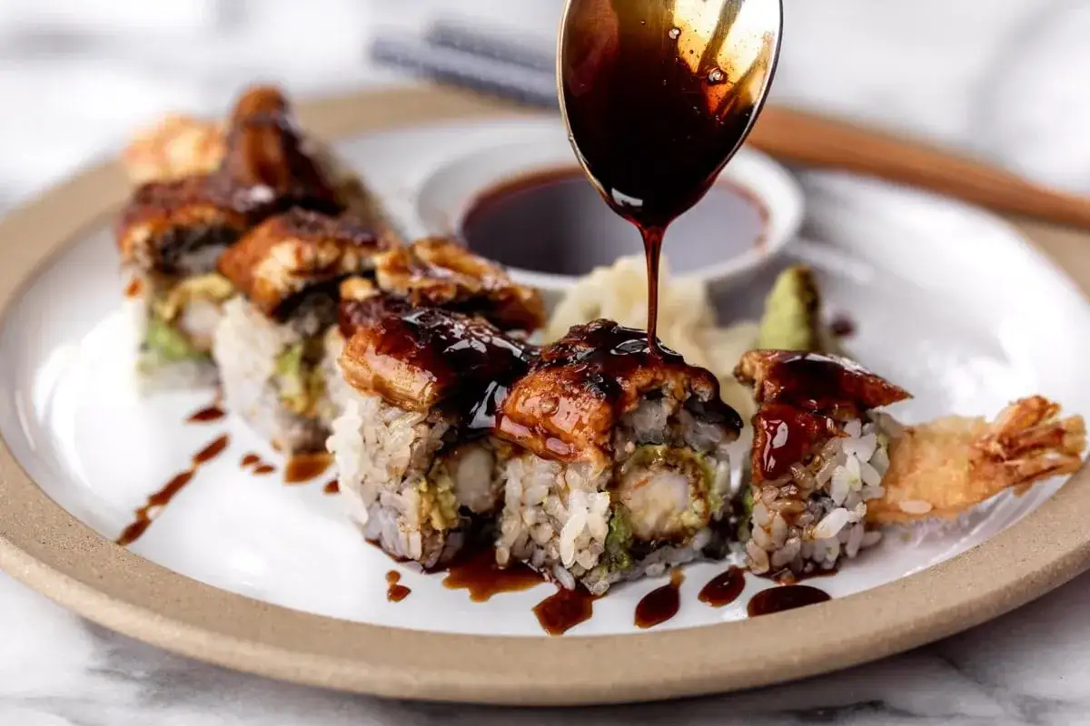 Rolka sushi z krewetką w tempurze i awokado, polana błyszczącym sosem unagi.