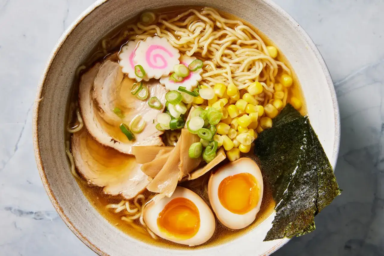 Miseczka aromatycznego shoyu ramen z makaronem, plastrami wieprzowiny, jajkiem na miękko, kukurydzą, bambusem i nori.