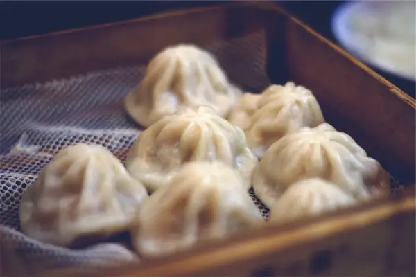 Pyszne, parujące dim sum w bambusowym koszyku. Delikatne pierożki kuszą swoim wyglądem.